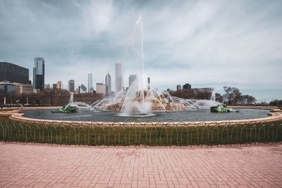 Fountain in city against sky