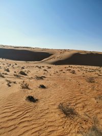 Sand dunes in desert against clear sky