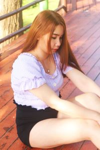 Young woman looking down while sitting outdoors