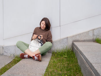 Woman is crocheting outdoor. tranquil leisure of female in urban park. anti-stress hobby.