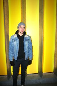 Portrait of man standing against yellow wall