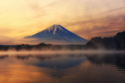 Mountain fuji with reflection and mist on water of lake shoji shojiko at sunrise, yamanashi, japan.