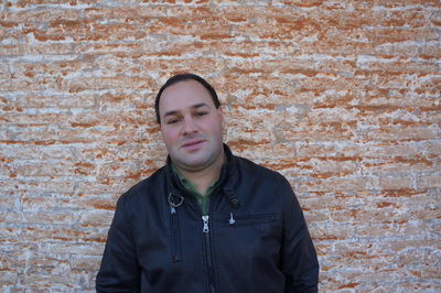 Man standing against brick wall