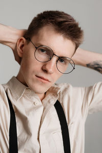 Close-up portrait of young man wearing eyeglasses against white background