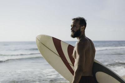 Young man on beach against sky