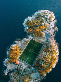 Aerial view of rock formation and soccer field against sea