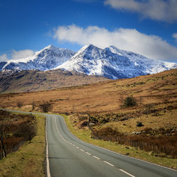 Road amidst snowcapped mountains against sky