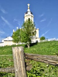 Wooden fence by tree against sky