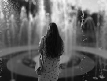 Rear view of woman standing against waterfall