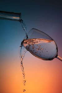 Close-up of water drop on stem against sky during sunset