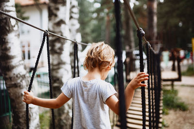 Girl child playing on a rope in the outdoor playground, adventure park.