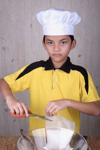 Boy wearing chef hat preparing food in kitchen at home