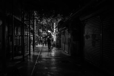 People walking on footpath amidst buildings in city at night