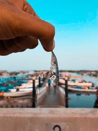 Man holding fishing net in sea against sky