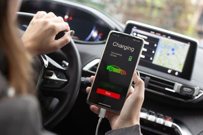 Midsection of person using mobile phone in car