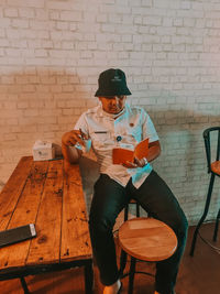 Man sitting on chair against wall