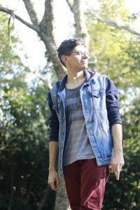 Man looking away while standing by tree at park