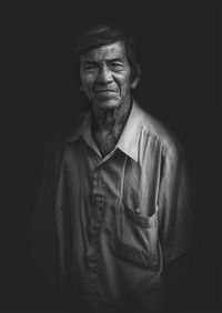 Portrait of man standing against black background