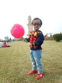 Full length of boy standing on balloons against sky