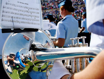 Cropped hand playing trumpet in city during event