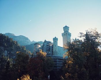 Trees and buildings against clear blue sky