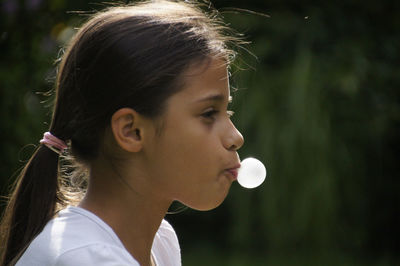 Close-up of girl blowing bubble gum outdoors