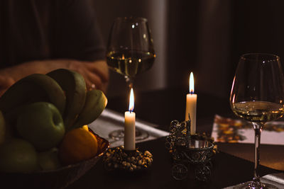 Close-up of candles and wineglasses by fruits on table