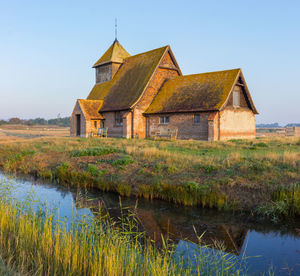 Old building by lake against sky