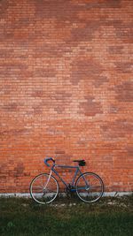 Bicycle parked against brick wall