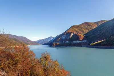 Scenic view of lake and mountains against clear blue sky