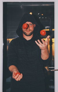 Portrait of man playing with tomatoes