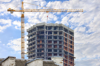 A tower crane works on the construction site of a modern multi-storey residential building.