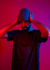 Portrait of young man standing against red background