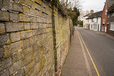 Road by wall and buildings in city