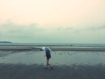 Woman standing on beach against sky