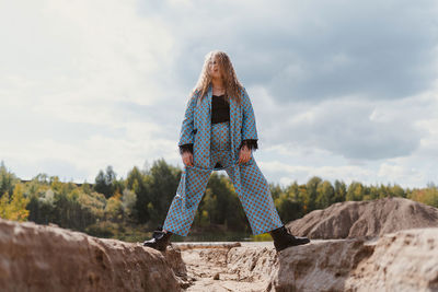 Rear view of woman standing on  fissure in the ground against sky