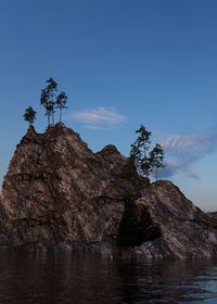 Rock formation by tree against blue sky