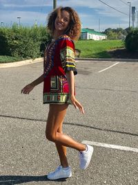 Side view of woman smiling while standing on footpath