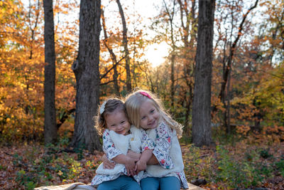 Portrait of happy girl with arms outstretched against trees