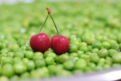 Two beads of cherry in the middle of peas