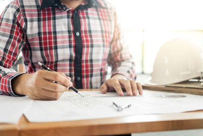 Midsection of man holding paper on table
