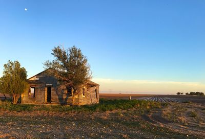 House on field against clear blue sky