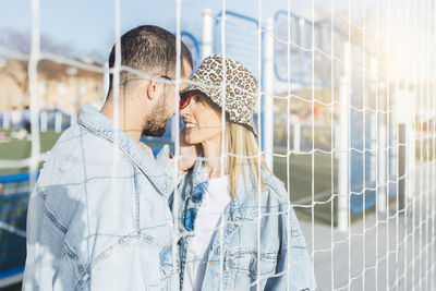 Girlfriend and boyfriend in the fence looking each other and touching noses. happy couple.