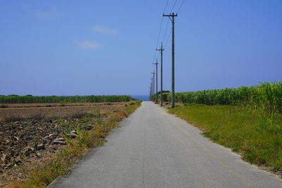 Road amidst field against sky