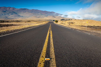 Empty road amidst landscape against sky