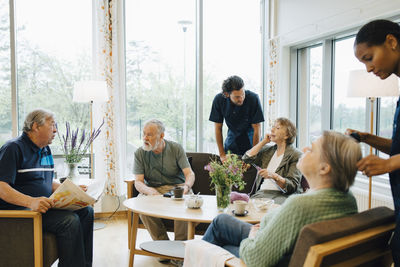 Male and female nurses taking care of elderly retired people at nursing home