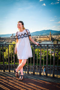 Woman standing by railing against sky