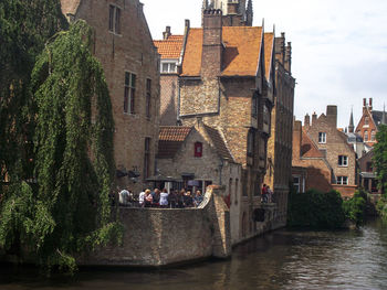 People on river amidst buildings against sky