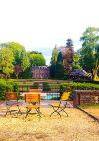 Chairs and table by trees against sky