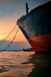 Boat moored on sea against sky during sunset
